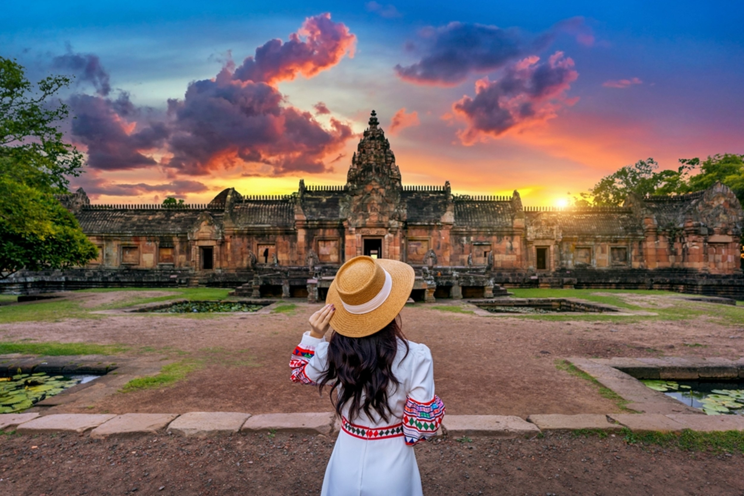 femeie priveste un templu la apus in Thailanda